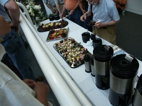2001 Mercury Grand Marquis - A buffet table is set up with various food items and coffee makers, attended by several people.