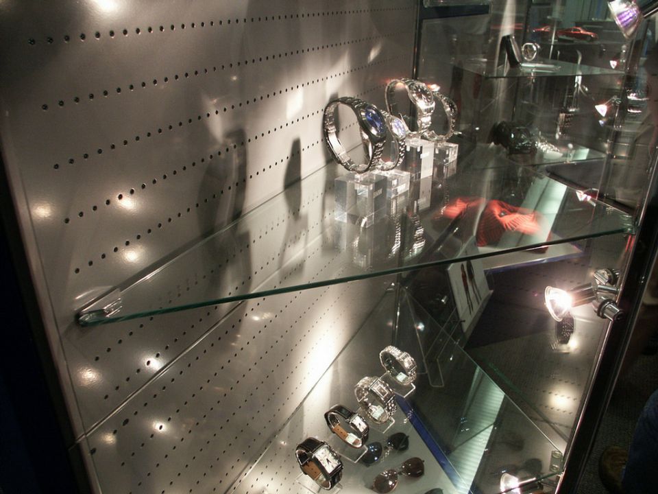 Watches displayed in a glass case with metal pegboard background