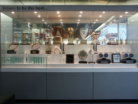 2001 Mercury Grand Marquis - A display case filled with various trophies and awards, including clocks, with the motivational phrase 'Driven to be the best...' above.