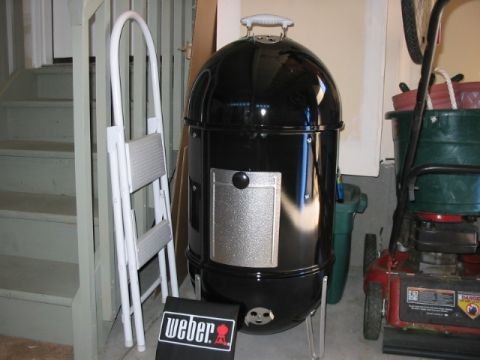 1995 Ford Bronco - A black Weber smoker is stored indoors next to a white folding ladder and a red lawnmower.