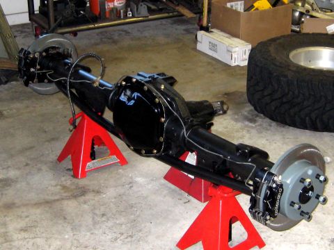 1996 Ford Bronco - A rear axle assembly, likely from a truck or SUV, is supported by red jack stands in a garage setting.
