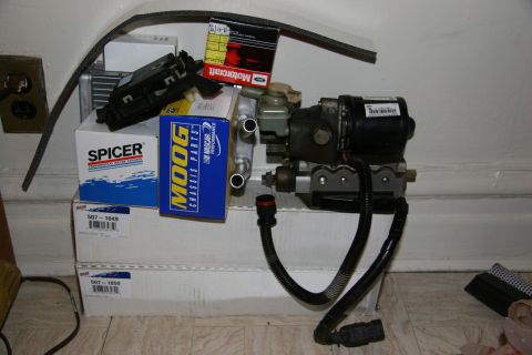 1992 Ford Taurus - Various automotive parts, including a brake actuator, are piled up on the floor.