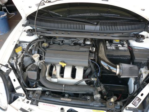 1996 Ford Probe - The engine bay of a white car displays an SRT-4 engine cover and an aftermarket air intake system.