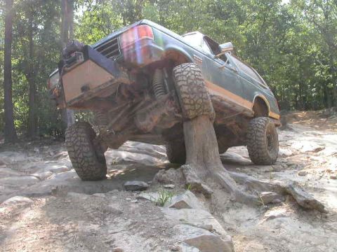 1990 Ford Bronco - This modified SUV is stuck on a tree stump on a rough, wooded trail.
