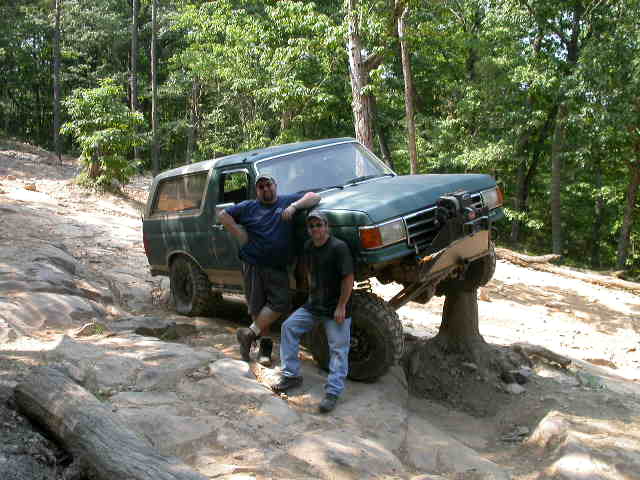 1990 Ford Bronco on rocky trail with two people standing next to it