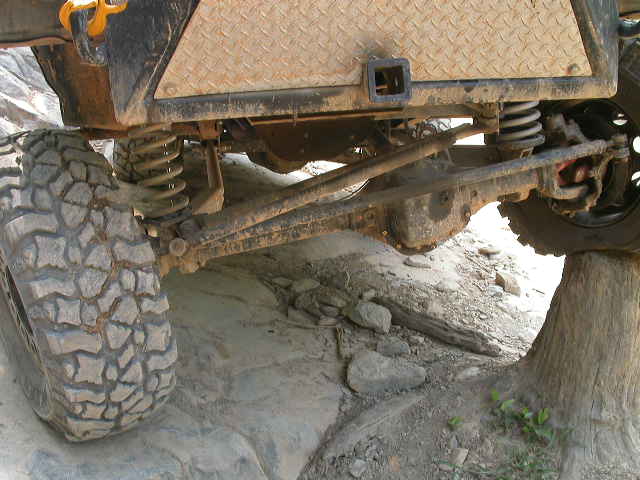Close-up of off-road vehicle's rear suspension and tire on rocky terrain