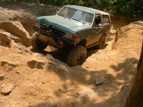 1990 Ford Bronco - This 1990 Ford Bronco is shown tackling a challenging off-road course with its robust tires and lifted suspension.