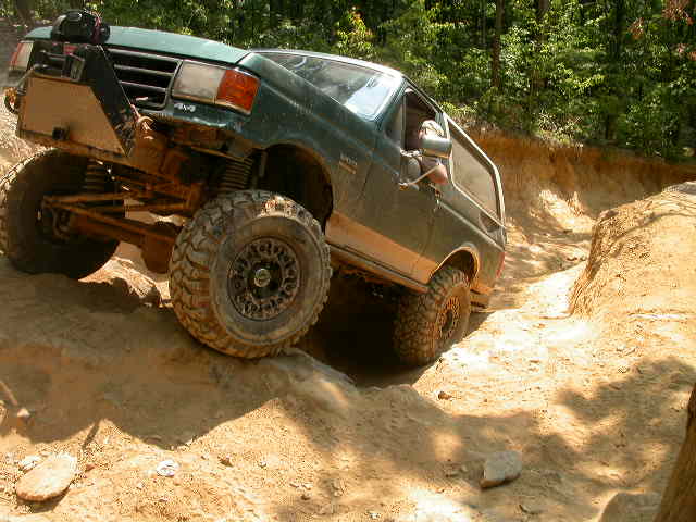 1990 Ford Bronco climbing a steep dirt trail with large tires
