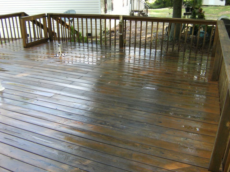 Wet wooden deck with railings and stairs, water pooling on planks