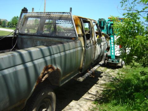 1992 Ford Bronco - A severely damaged pickup truck, likely a Ford F-350, is being towed by a service truck after a fire.