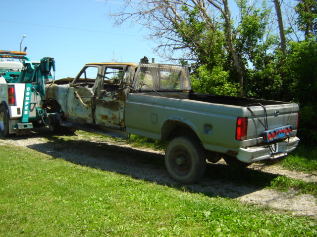 Burned-out 1990 Ford F-350 pickup truck on tow truck