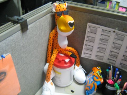 1988 Mercury Grand Marquis - Chester Cheetah figure perched on a disinfectant-wipes canister in a fabric-walled office cubicle.