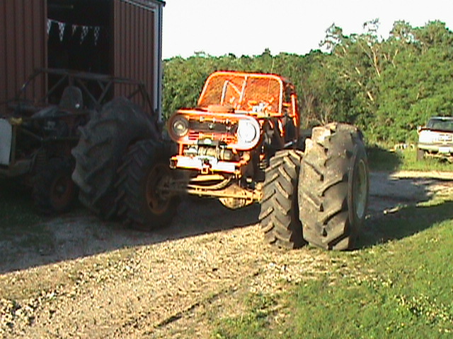 Orange monster truck with massive tires and roll cage