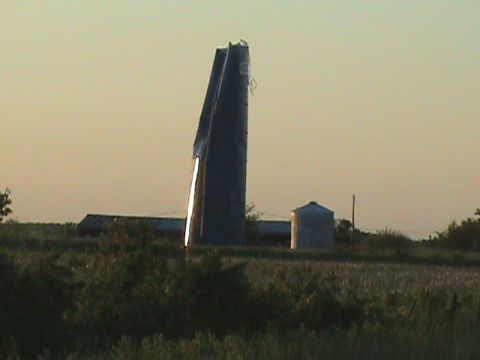 1973 Ford Bronco - A farm scene with a damaged silo and a smaller grain bin under a hazy sky.