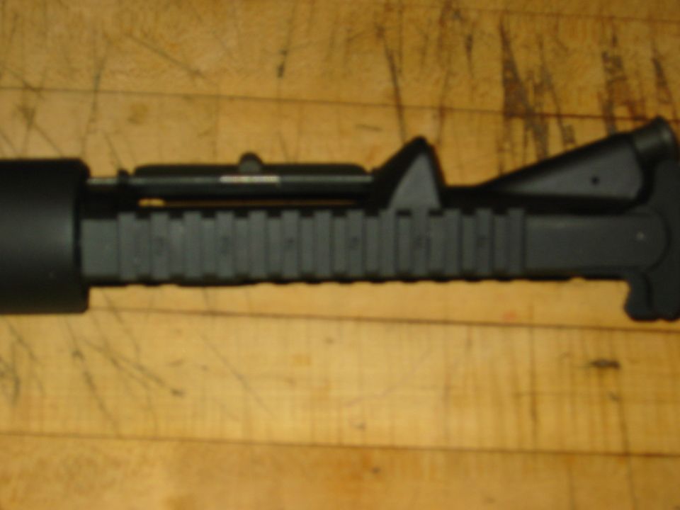 Close-up of a black firearm accessory with rail segments and a sight
