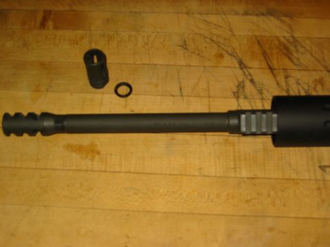 1996 Ford Bronco - A gun barrel with attached muzzle brake, a separate cap, and a ring are laid out on a wooden surface.