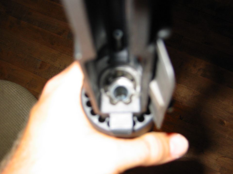 Hand holding a gray mechanical component with visible gears and a bolt