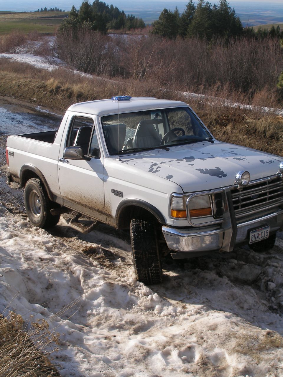 White Ford Bronco on a snowy, muddy road