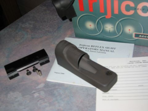 1996 Ford Bronco - A Trijicon Reflex Sight Operators Manual and associated parts are laid out on a patterned surface.