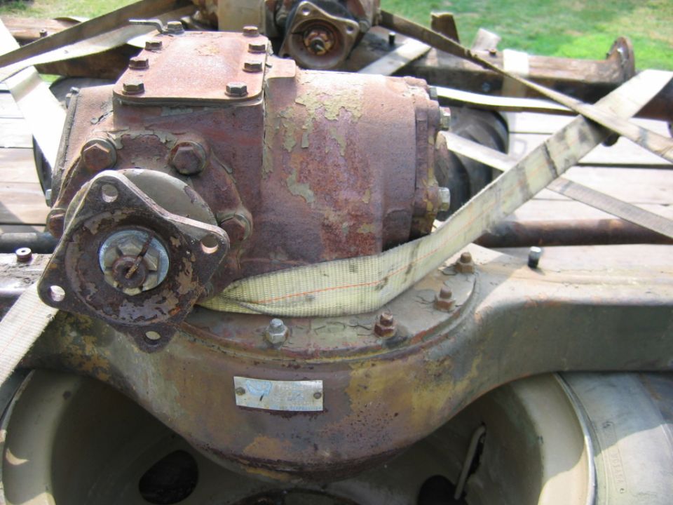 rusty differential assembly with straps around it, sitting on a trailer