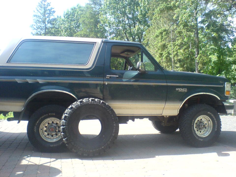 1985 Ford Bronco side view, dark green and tan with spare tire