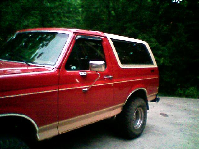 Side view of red lifted Ford Bronco with white removable hardtop