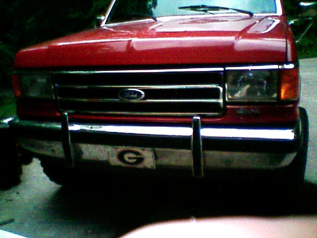 Front grille and chrome bumper of red Ford truck with 4x4 badge