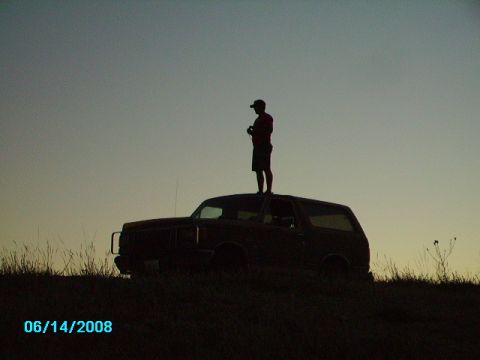 1990 Ford Bronco - A person stands atop a Ford Bronco silhouetted against the sky at dusk.