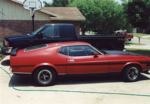 1971 Ford Mustang - A red 1971 Ford Mustang Mach 1 is parked in front of a black pickup truck.