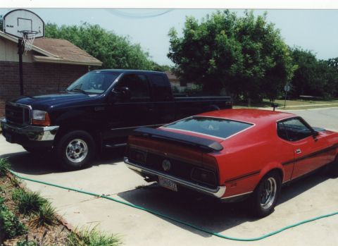 1971 Ford Mustang - A red 1971 Ford Mustang Mach 1 is parked next to a black Ford F-250 truck in a driveway.