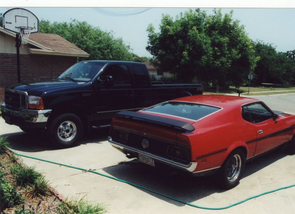 Red Ford Mustang fastback and dark Ford pickup parked on a driveway