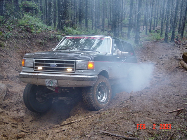 Ford Bronco driving off-road, kicking up smoke