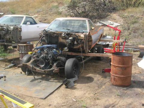 1975 Ford Ranchero - A disassembled 1970s era pickup truck or El Camino is shown outdoors in a yard with a second vehicle in the background. The foreground vehi…