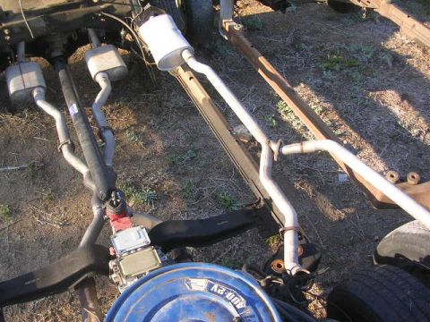 1975 Ford Ranchero - The underside of a vehicle chassis is shown, featuring a dual exhaust system with two mufflers and a driveshaft. A blue air cleaner assembl…