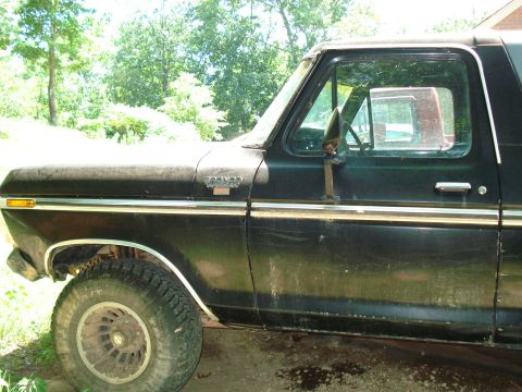 1989 Ford Bronco - The driver's side of a black Ford Bronco is shown parked outdoors. The vehicle has a chrome trim line running along the side and a visible…