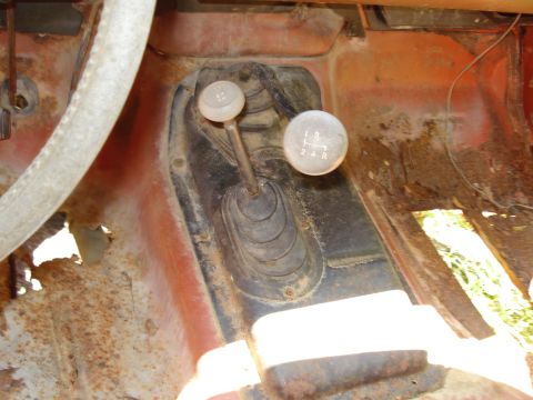 1989 Ford Bronco - The interior of a vintage vehicle shows a manual transmission shifter with a four-speed pattern (1, 2, 3, 4, R) on the knob. The surroundin…