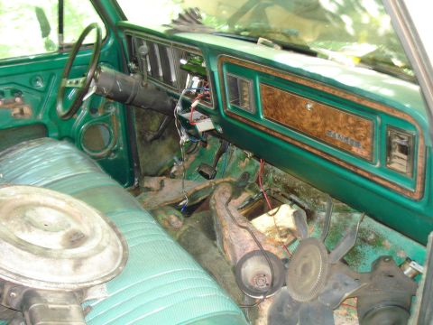 1989 Ford Bronco - The interior of a vintage green Ford truck, showing the dashboard, steering wheel, and a portion of the passenger seat. The dashboard featu…