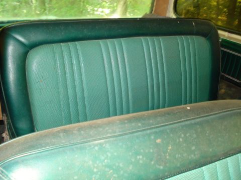 1989 Ford Bronco - The interior of a vintage vehicle shows a green vinyl bench seat with vertical pleating. The seat appears to be in a state of disrepair, wi…
