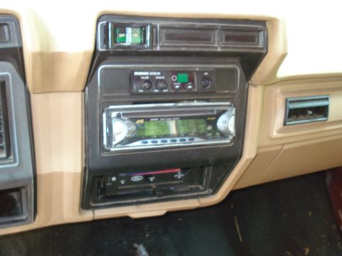 1989 Ford Bronco - The interior of a vehicle shows a tan dashboard with a JVC car stereo installed. Above the stereo is a smaller radio unit and a green "OFF…