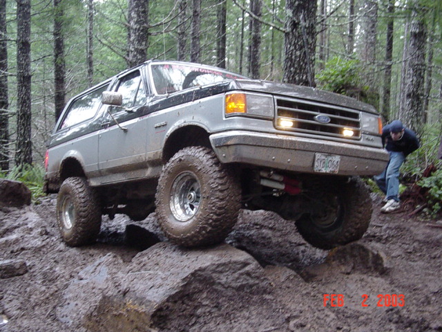 Gray Ford Bronco off-roading on rocks and mud