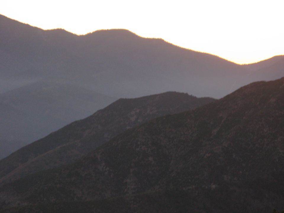 Layered mountain ridgelines silhouetted in haze at sunset