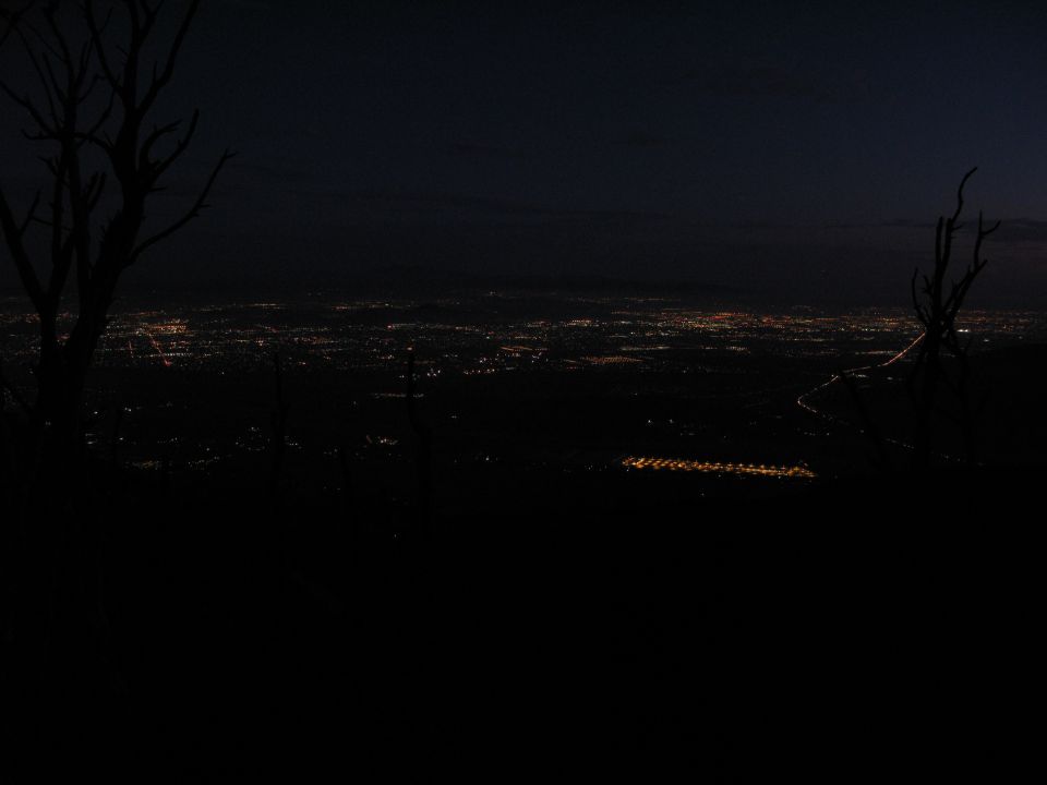 City lights in a valley at night seen from a dark hillside