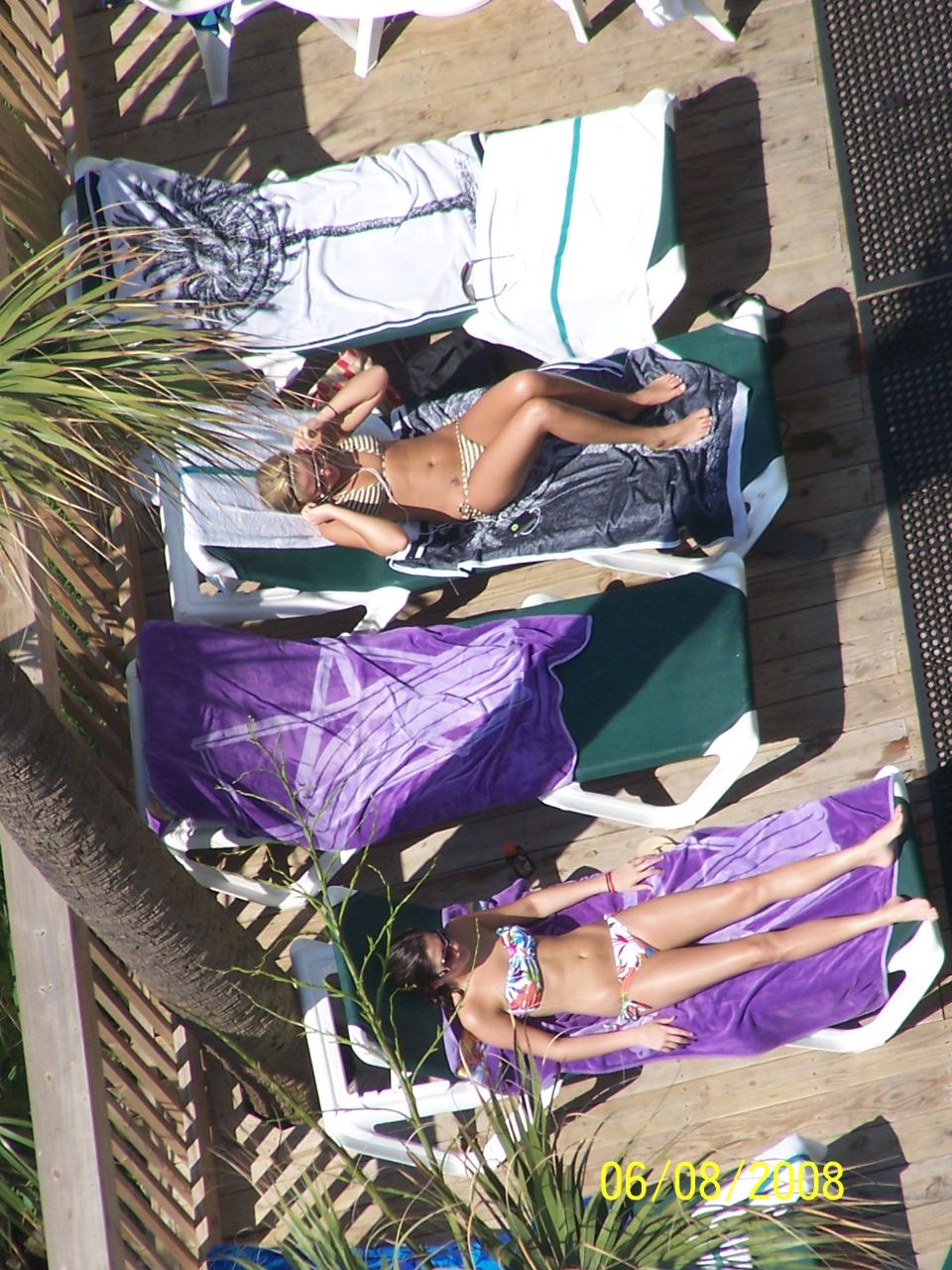 Photo of people sunbathing on lounge chairs on a wooden deck