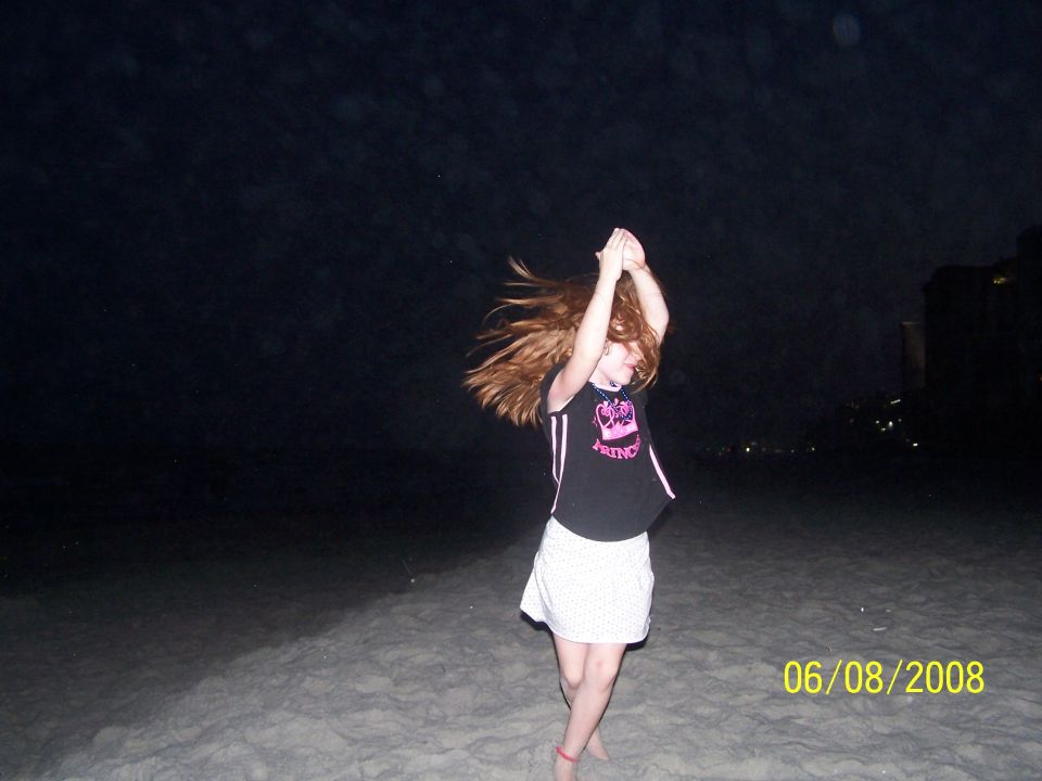 Photo of a child dancing on a beach at night