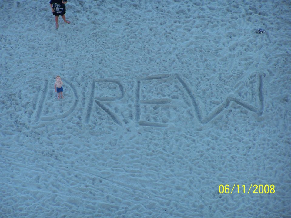 Aerial photo of the name 'Drew' written large in beach sand