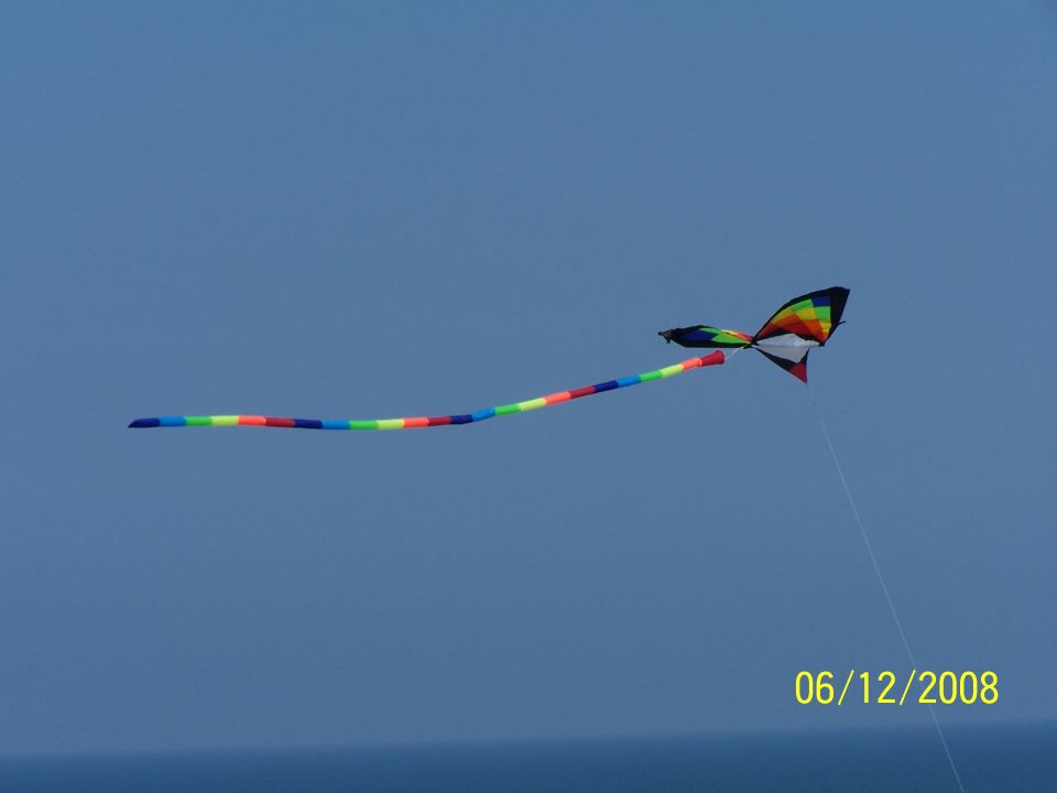 Photo of a rainbow delta kite with long streamer tail in the sky