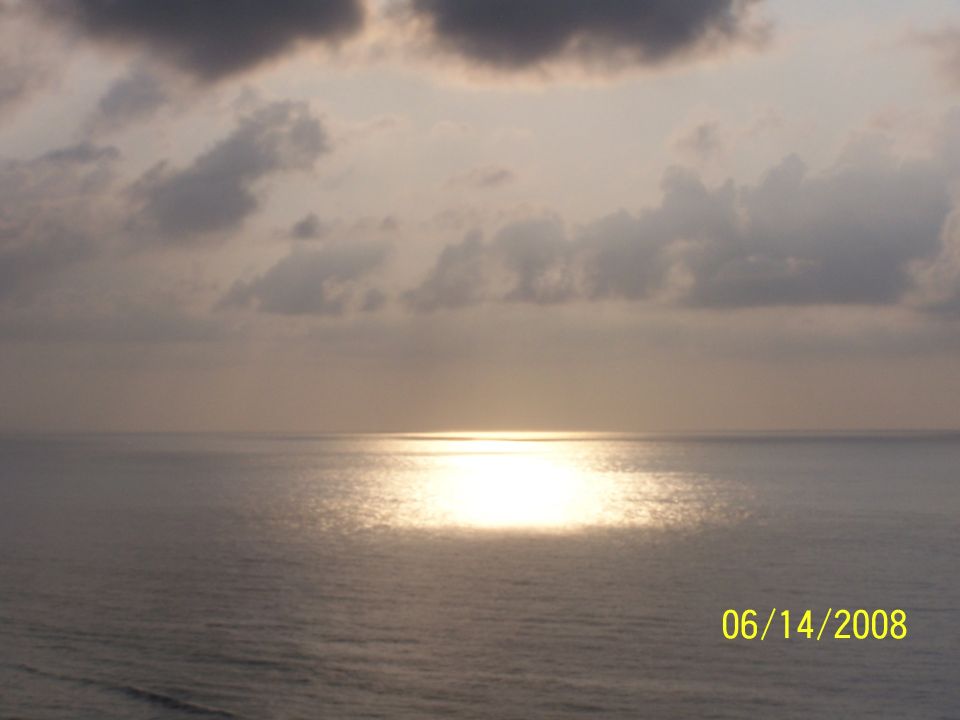 Photo of a cloudy sunset over the ocean with sun reflection on water