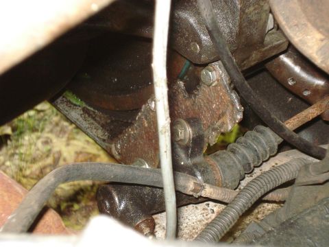 1989 Ford Bronco - A close-up view of the clutch slave cylinder and related hydraulic line, mounted to the transmission bell housing of a vehicle. The compone…