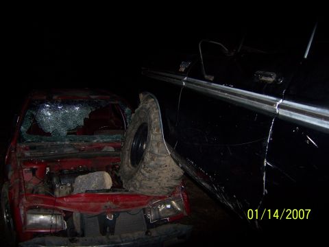 1989 Ford Bronco - A red car with a shattered windshield is parked next to a black vehicle. The front of the red car is heavily damaged, with the hood open an…