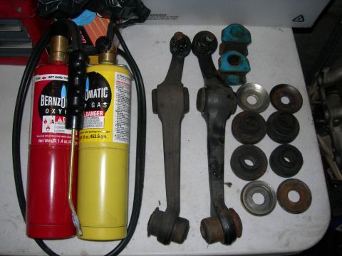 1992 Ford Taurus - A Bernzomatic oxygen and propane torch set is laid out next to a collection of automotive suspension parts, including control arms and bush…